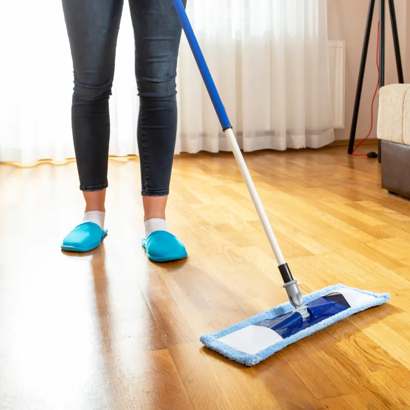 Woman sweeping laminate floor with microfiber